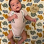 baby, infant, blanket, animal_pattern, onesie, striped_clothing, bow_tie, wooden_sign, heart_shape, milestone, cute, lying_down, portrait, child, young_baby, soft_texture, colorful, decorative, indoor, face