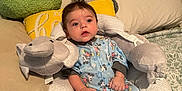Thomas is registered to the contest to win money with this photo: baby, infant, mickey_mouse, onesie, plush_toy, elephant_pillow, stuffed_animal, raccoon, cushion, bed, blanket, pajamas, child, indoor, soft_toys, cute, sleepwear, relaxed, person, young_child