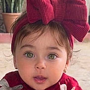 Mila participe au concours pour gagner de l'argent avec cette photo : toddler, child, face, green_eyes, red_sweater, headband, bow, cute, portrait, outdoor, plant, potted_plant, expression, curious, young_child, fashion, winter_clothing, person, baby, closeup