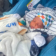 Carlos Jr is registered to the contest to win money with this photo: baby, newborn, sleeping, infant_car_seat, blanket, hat, striped_clothing, colorful_hat, pacifier, blue_fabric, cozy, child, cute, resting, indoors, soft_texture, bundle, peaceful, car_seat, warning_label
