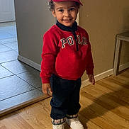 Liam joined the competition — help win amazing prizes! casual_clothing, child, curly_hair, door, footwear, happy, headwear, indoor, jeans, person, polo, red_cap, red_sweater, smiling, standing, tile_floor, wall, white_shoes, wooden_floor, young