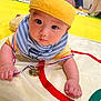 baby, headband, bib, medal, ribbon, yellow, striped, toddler, child, indoor, mat, person, curious, face, hand, event, people, sitting, background, closeup
