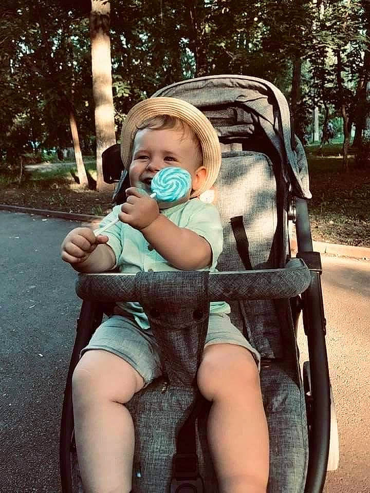 Marco is registered to the contest to win money with this photo: baby, baby_carriage, baby_toddler_clothing, child, cool, grass, happy, human, leisure, mammal, people_in_nature, person, plant, sunlight, thigh, tints_and_shades, tire, toddler, tree, vertebrate