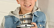 Timoté participe au concours pour gagner de l'argent avec cette photo : boy, camera, casual_clothing, child, cute, denim_jacket, hands, happy, hoodie, indoor, person, photography, portrait, short_hair, smile, standing, striped_shirt, vintage_camera, white_wall, young