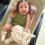 Mia joined the competition — help win amazing prizes! baby, infant, smiling, green_clothing, white_socks, plush_toy, bunny_toy, teether, baby_seat, blanket, indoor, happy, cute, child, person, portrait, soft_lighting, cushion, relaxed, playful