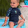 Liano participe au concours pour gagner de l'argent avec cette photo : toddler, child, beach, sand, swimsuit, smile, wet_hair, palm_leaves, towel, sunshine, vacation, outdoor, cute, happy, summer, sitting, playful, water_drops, red_bracelet, blue_clothing