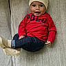baby, child, smiling, red_shirt, hat, beige, polo, jeans, socks, couch, furniture, indoor, cute, happy, portrait, person, sitting, infant, young_child, casual_clothing