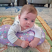 Kendell joined the competition — help win amazing prizes! baby, infant, child, portrait, sitting, unicorn_pillow, pillow, quilt, blanket, rug, living_room, armchair, furniture, indoors, face, blue_eyes, brown_hair, white_shirt, colorful, cute