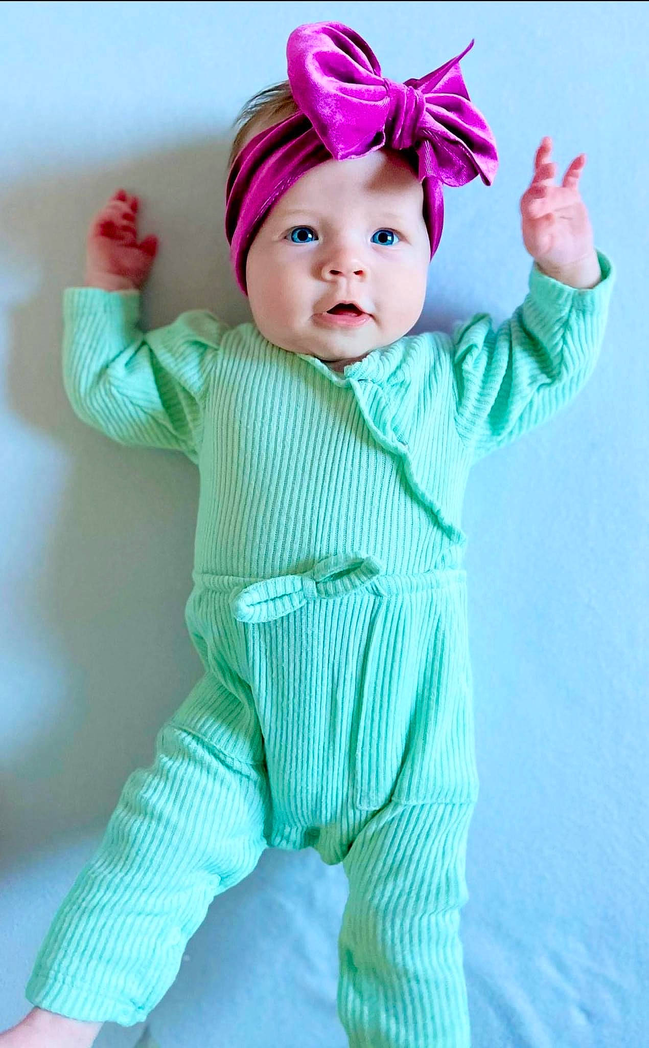 Madeline is registered to the contest to win money with this photo: arm, baby, baby_toddler_clothing, cap, child, costume_hat, electric_blue, face, hair_accessory, happy, hat, head, headband, headpiece, headwear, outerwear, pattern, person, pink, sleeve