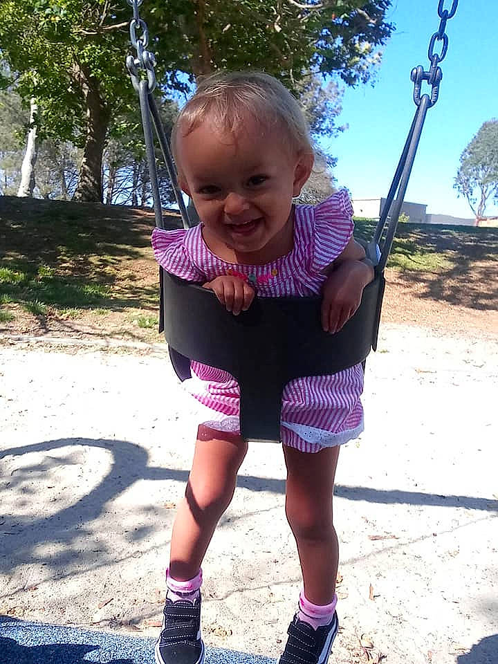 Alissa joined the competition — help win amazing prizes! baby, child, fun, happy, joy, outdoor_play_equipment, person, pink, plant, play, playground, public_space, purple, recreation, shorts, smile, summer, swing, toddler, tree