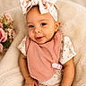 baby, child, infant, headband, bow, pink_bib, smiling, cute, portrait, soft_texture, floral_pattern, flower, comfort, cozy, sitting, clothing, person, happy, indoors, closeup