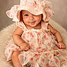 Amira joined the competition — help win amazing prizes! baby, child, hat, dress, cherry_pattern, smile, sitting, fluffy, cute, portrait, infant, apparel, headwear, fabric, soft, happy, young_child, indoors, skin, footwear