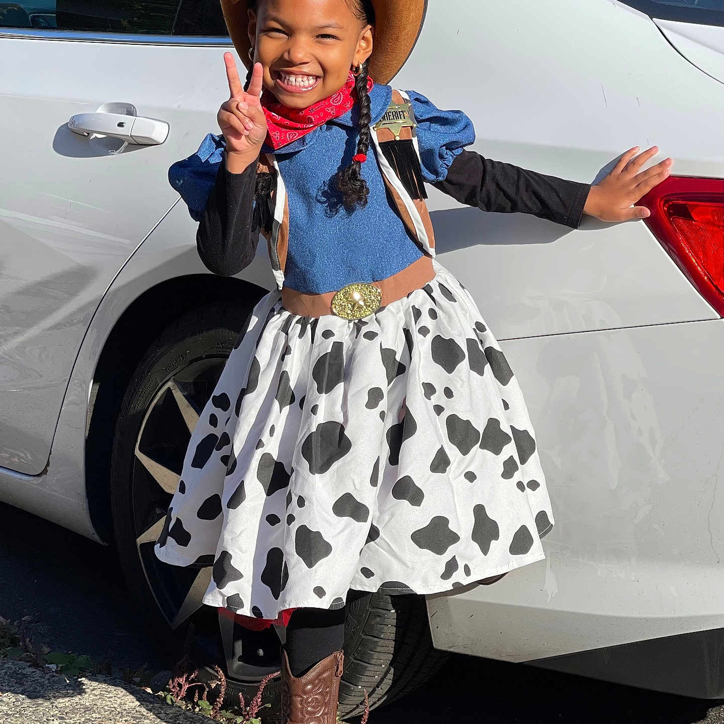 Novalee Summer is registered to the contest to win money with this photo: accessories, bandana, boots, braids, car, child, costume, cowboy, dress, fashion, happy, hat, outdoor, peace_sign, person, playful, posing, smile, street, sunlight
