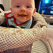 Christopher joined the competition — help win amazing prizes! baby, child, messy_face, high_chair, indoor, smiling, food_stains, bib, seat, person, cute, happy, infant, face, head, clothing, home, television, background, furniture