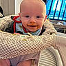 Christopher joined the competition — help win amazing prizes! baby, child, smiling, messy_face, bib, baby_seat, indoor, furniture, crib, patterned_fabric, happy, infant, person, closeup, cute, playful, seated, home, face, bright_eyes