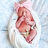 newborn, baby, infant, blanket, headband, pink_bow, hospital_id, umbilical_clamp, bedspread, floral_pattern, skin, wrapped, resting, sleeping, cute, small, person, indoors, soft, peaceful