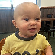 Donald is registered to the contest to win money with this photo: baby, casual, chair, child, curious, expression, face, furniture, indoor, person, restaurant, short_hair, sitting, skin, smiling, table, toddler, window, wooden_table, yellow_shirt