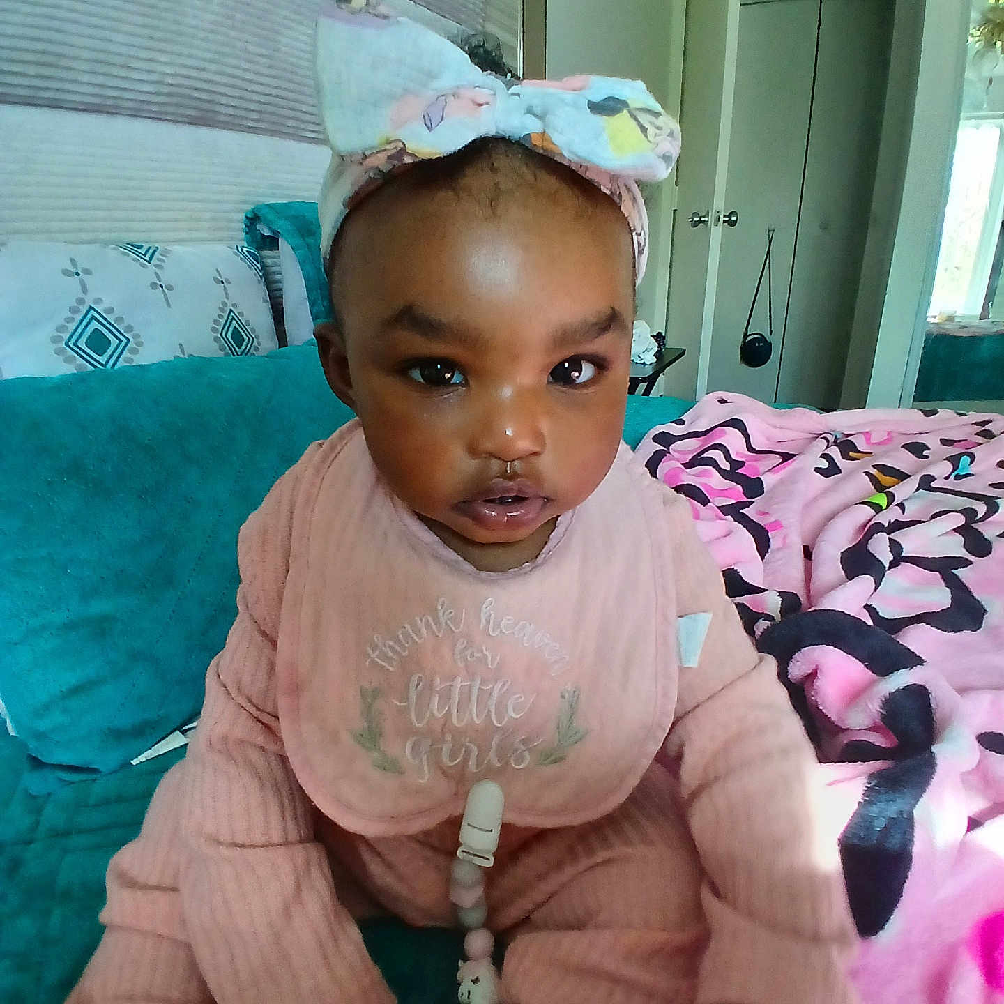 Naomi joined the competition — help win amazing prizes! baby, child, girl, headband, pink, bib, couch, blanket, indoor, home, curious, clothing, person, face, portrait, seated, furniture, soft, colorful, cozy