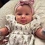 Scarlett is registered to the contest to win money with this photo: baby, infant, girl, headband, pink, tongue_out, floral_dress, white_dress, smiling, cute, soft_blanket, lying_down, portrait, child, adorable, closeup, happy, indoor, person, baby_clothes