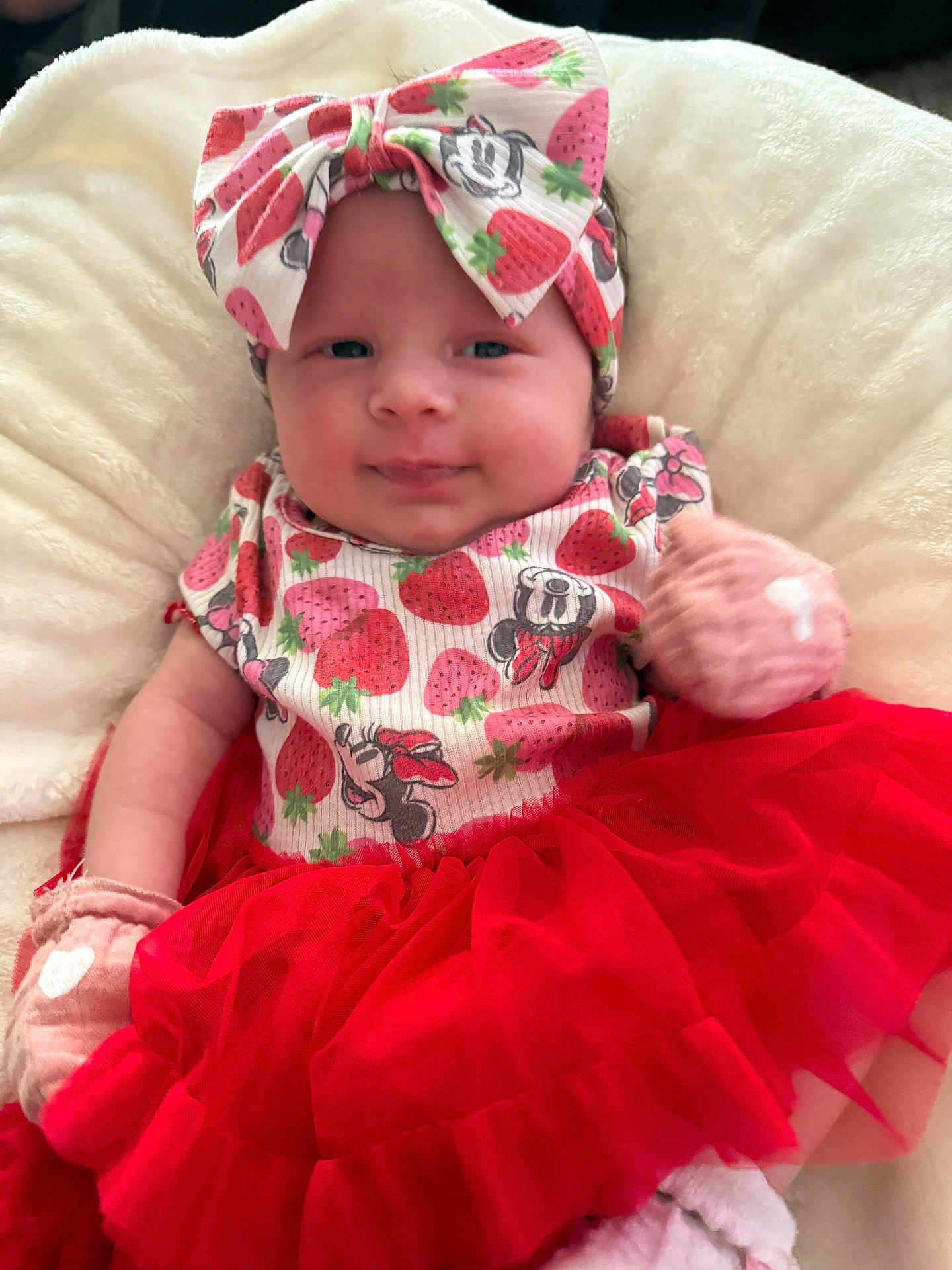 Scarlett is registered to the contest to win money with this photo: baby, infant, headband, bow, strawberry, red_skirt, tutu, gloves, soft_blanket, cute, smiling, clothing, portrait, child, lying_down, pink, white, happy, closeup, adorable