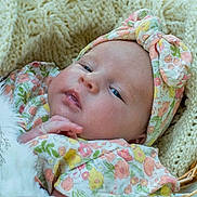 Scarlett is registered to the contest to win money with this photo: baby, infant, headband, floral_pattern, blanket, knitted, sleepy, face, hand, closeup, newborn, cute, soft_texture, portrait, resting, skin, young_child, cozy, indoor, basket