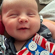 Scarlett is registered to the contest to win money with this photo: baby, smiling, face, infant, clothing, pattern, button, stars, stripes, fabric, pacifier, closeup, cute, soft, child, sleepy, portrait, indoor, person, happy