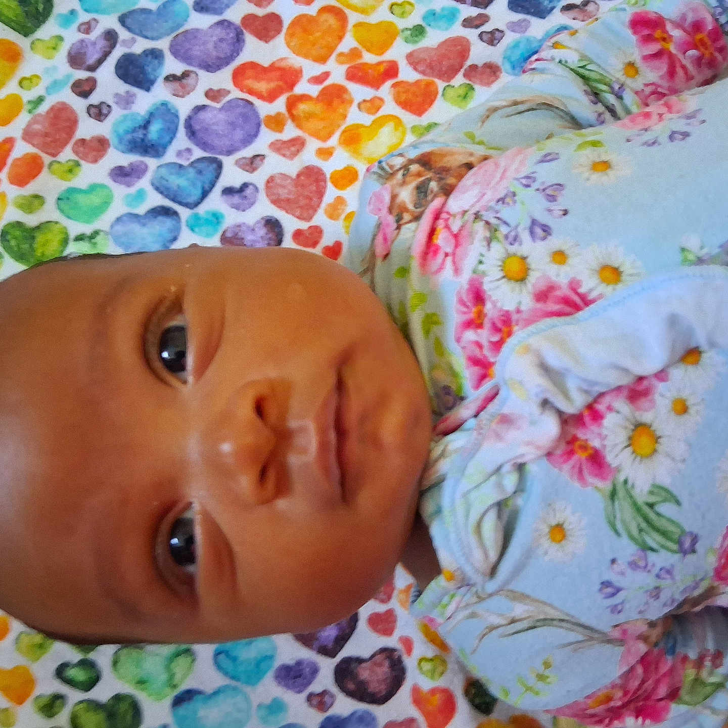 Makenzii joined the competition — help win amazing prizes! adorable, baby, blanket, child, closeup, colorful, cute, expression, eyes, face, floral_clothing, heart_pattern, indoors, infant, laying, newborn, pattern, person, portrait, soft