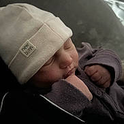 Liyana participe au concours pour gagner de l'argent avec cette photo : baby, newborn, sleeping, hat, clothing, face, hand, fist, purple, white, cozy, infant, peaceful, portrait, closeup, indoor, soft_light, cute, tiny, resting