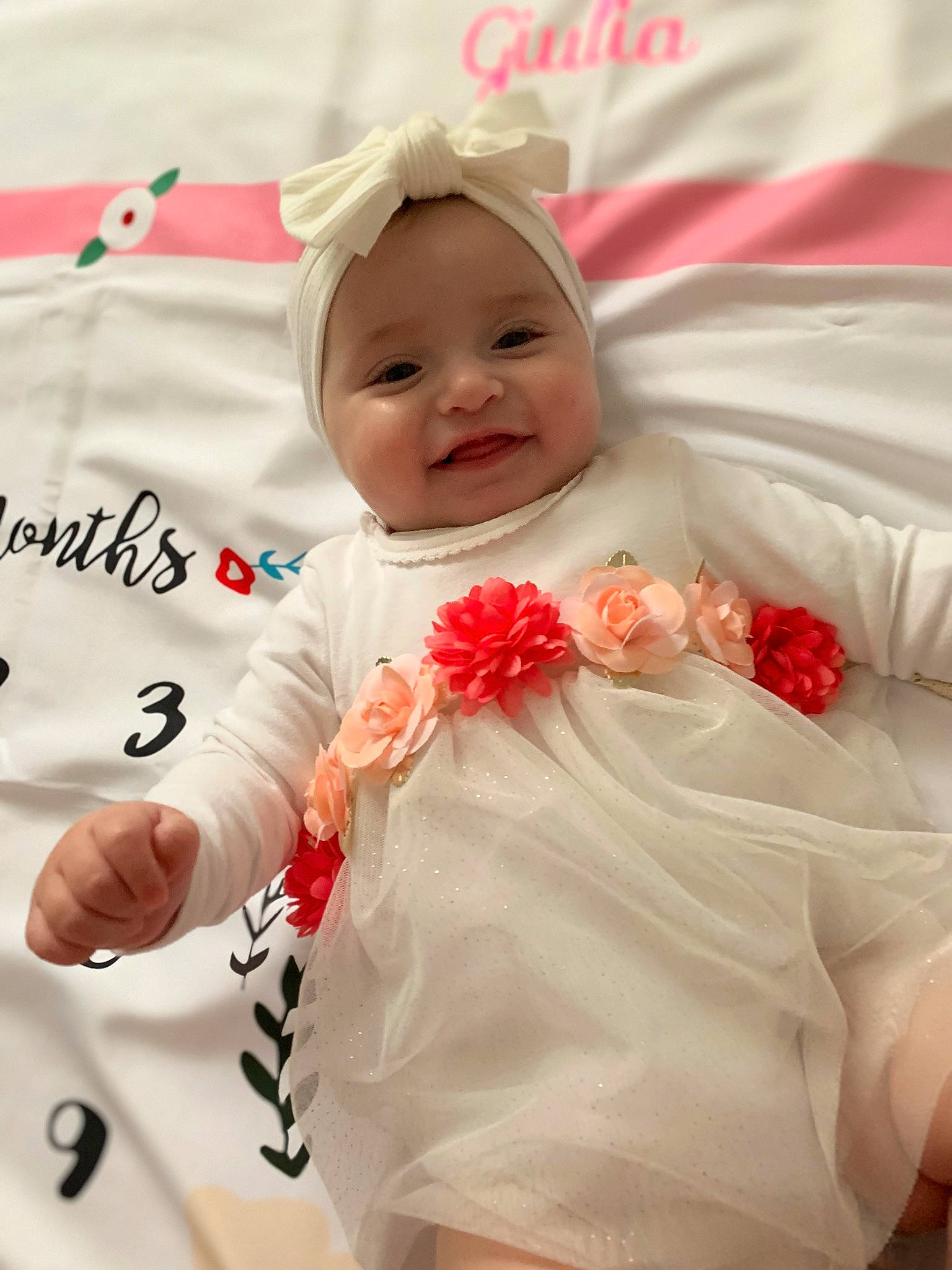 Giulia participe au concours pour gagner de l'argent avec cette photo : baby, baby_toddler_clothing, beauty, child, comfort, event, face, finger, gesture, happy, headwear, joy, linens, person, petal, pink, product, skin, sleeve, smile