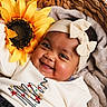 Ashley a rejoint le concours — aidez-le/la à gagner de superbes lots ! baby, smiling, headband, bow, sunflower, basket, blanket, cozy, infant, cute, portrait, happy, child, clothing, soft, indoor, warm, face, person, closeup