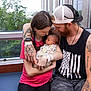 Ellie is registered to the contest to win money with this photo: newborn, baby, mother, father, tattoo, family, love, window, bench, indoor, floral_blanket, casual_clothing, beard, cap, watch, bracelet, holding, looking, parenting, together