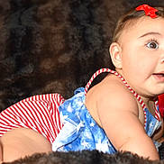 Audrey is registered to the contest to win money with this photo: baby, child, infant, cute, portrait, face, smile, red_bow, striped_clothing, blue_clothing, stars, blanket, soft_texture, indoors, happy, young, skin, eyes, expression, lying_down