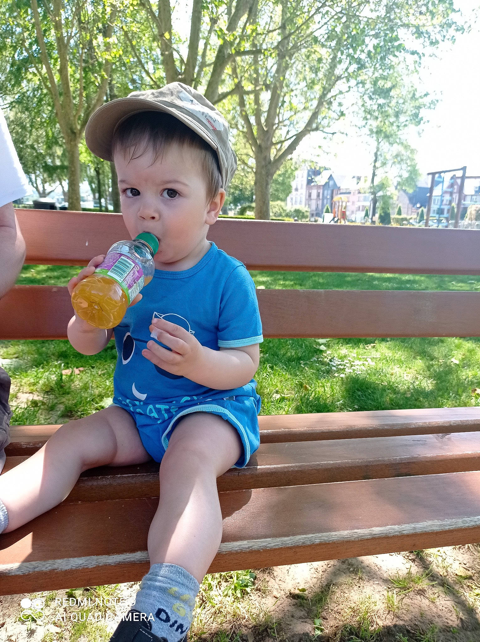 Gabin participe au concours pour gagner de l'argent avec cette photo : baby_toddler_clothing, bench, drinking_water, electric_blue, grass, happy, hat, human_leg, knee, leisure, outdoor_bench, outdoor_furniture, person, plant, plastic_bottle, recreation, shorts, t_shirt, thigh, toddler