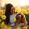 woman, dog, flower_field, daffodils, yellow_flowers, outdoor, spring, sunlight, nature, pet, portrait, happy, smiling, long_hair, casual_clothing, greenery, warm_light, affection, companionship, close_up