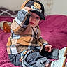 baby, blanket, cap, casual, child, cozy, cute, denim_pants, fashion, footwear, hat, indoor, pink_blanket, plaid_shirt, portrait, sitting, soft_texture, toddler, white_shoes, young_child