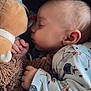 baby, sleeping, plush_toy, onesie, hand, face, ear, blanket, infant, cute, child, soft_texture, peaceful, cozy, resting, closeup, portrait, indoor, young_child, comfort