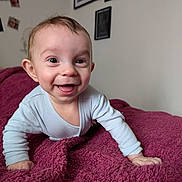 Malo a rejoint le concours — aidez-le/la à gagner de superbes lots ! baby, bed, blanket, closeup, cozy, crawling, cute, eyes, face, hands, happy, indoor, infant, onesie, picture_frame, portrait, rosy_cheeks, smile, soft_texture, wall_art