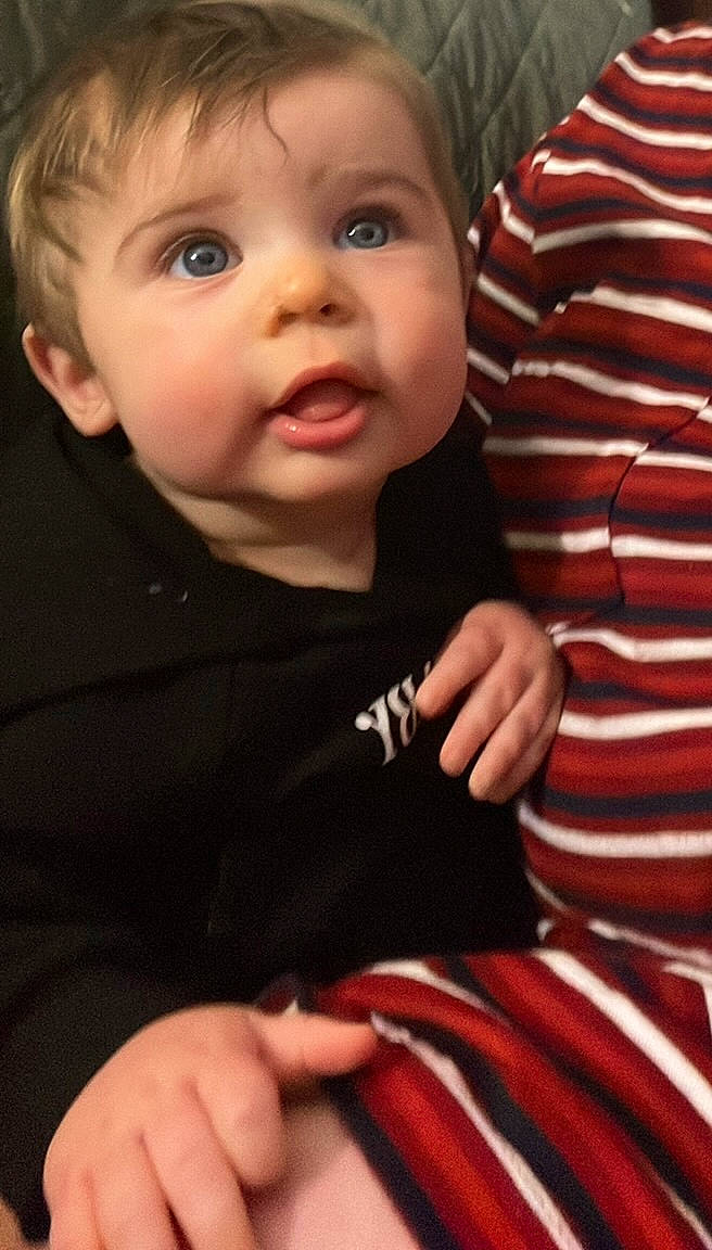 Devin is registered to the contest to win money with this photo: baby, baby_toddler_clothing, cheek, child, eye, eyelash, facial_expression, finger, gesture, hand, happy, iris, nose, outerwear, person, skin, sleeve, smile, t_shirt, thumb