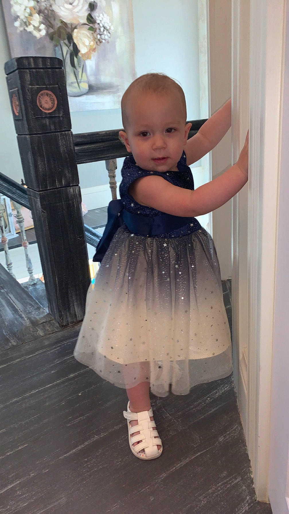 Oakley is registered to the contest to win money with this photo: baby, baby_toddler_clothing, child, day_dress, dress, embellishment, face, fashion_design, flash_photography, flooring, formal_wear, happy, leg, one_piece_garment, pattern, person, shoulder, sleeve, standing, toddler