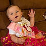 baby, birthday, celebration, child, clothing, couch, cute, dots, face, gold, happy, indoors, party, person, pink, sash, seated, smile, tutu, waving