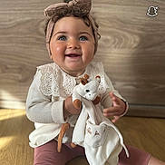 Soheila participe au concours pour gagner de l'argent avec cette photo : baby, blue_eyes, bow, child, clothing, cute, floor, giraffe, happy, headband, indoors, long_sleeve, pink_leggings, plush_toy, sitting, smiling, toddler, toy, wooden_background, wooden_floor