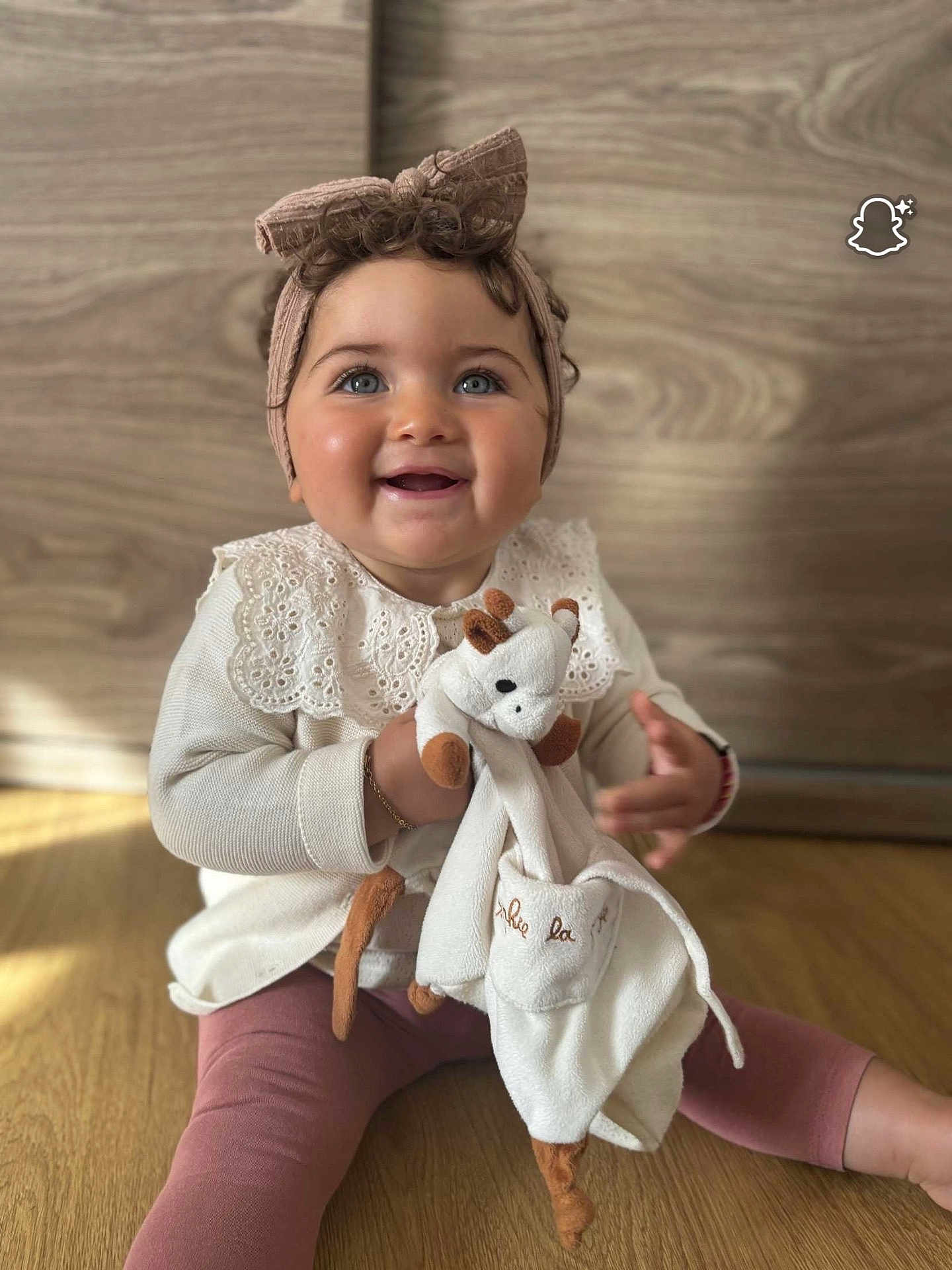 Soheila participe au concours pour gagner de l'argent avec cette photo : baby, blue_eyes, bow, child, clothing, cute, floor, giraffe, happy, headband, indoors, long_sleeve, pink_leggings, plush_toy, sitting, smiling, toddler, toy, wooden_background, wooden_floor