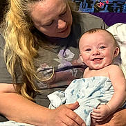 Evan is registered to the contest to win money with this photo: baby, woman, blanket, smile, happy, indoor, person, holding, child, quilt, hair, face, clothing, toddler, seated, hands, blanket_pattern, skin, portrait, family