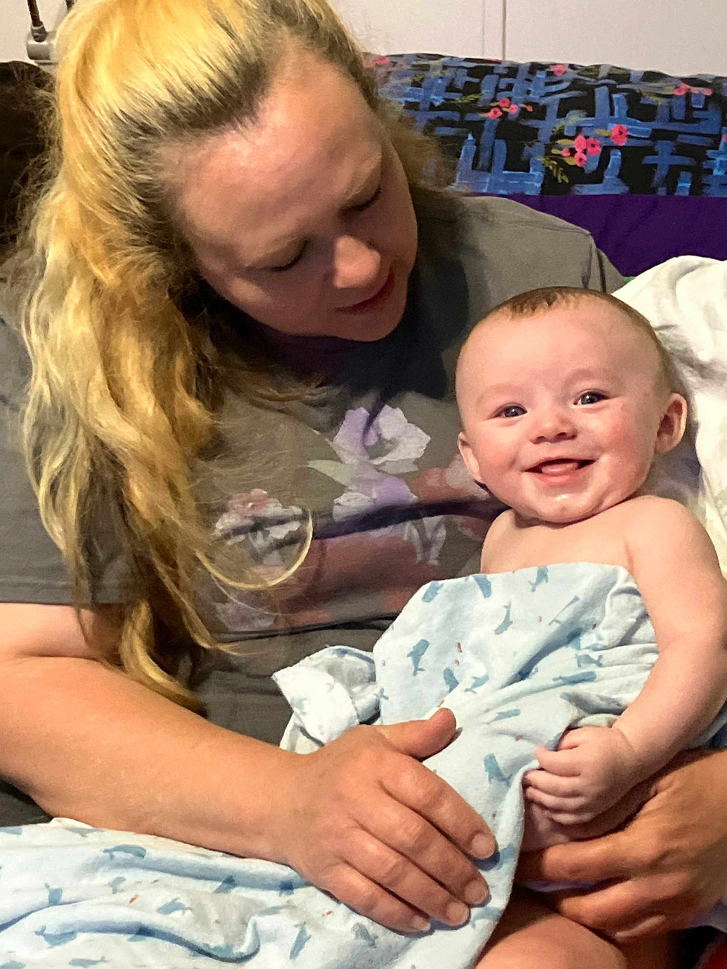 Evan is registered to the contest to win money with this photo: baby, woman, blanket, smile, happy, indoor, person, holding, child, quilt, hair, face, clothing, toddler, seated, hands, blanket_pattern, skin, portrait, family