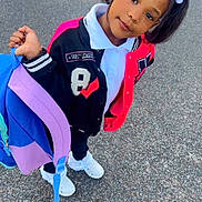 Miss Naomi joined the competition — help win amazing prizes! child, girl, backpack, pavement, outdoor, portrait, smiling, hair_ties, jacket, sneakers, casual_clothing, playful, young_person, pigtails, white_shirt, black_pants, colorful, holding, standing, cute