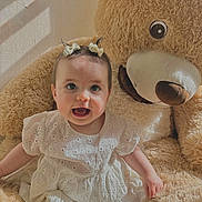 Luna a rejoint le concours — aidez-le/la à gagner de superbes lots ! baby, bows, child, cozy, cute, hair_accessories, happy, indoor, infant, playful, plush_toy, portrait, seated, shadow, smiling, soft_texture, sunlight, teddy_bear, warm_lighting, white_dress