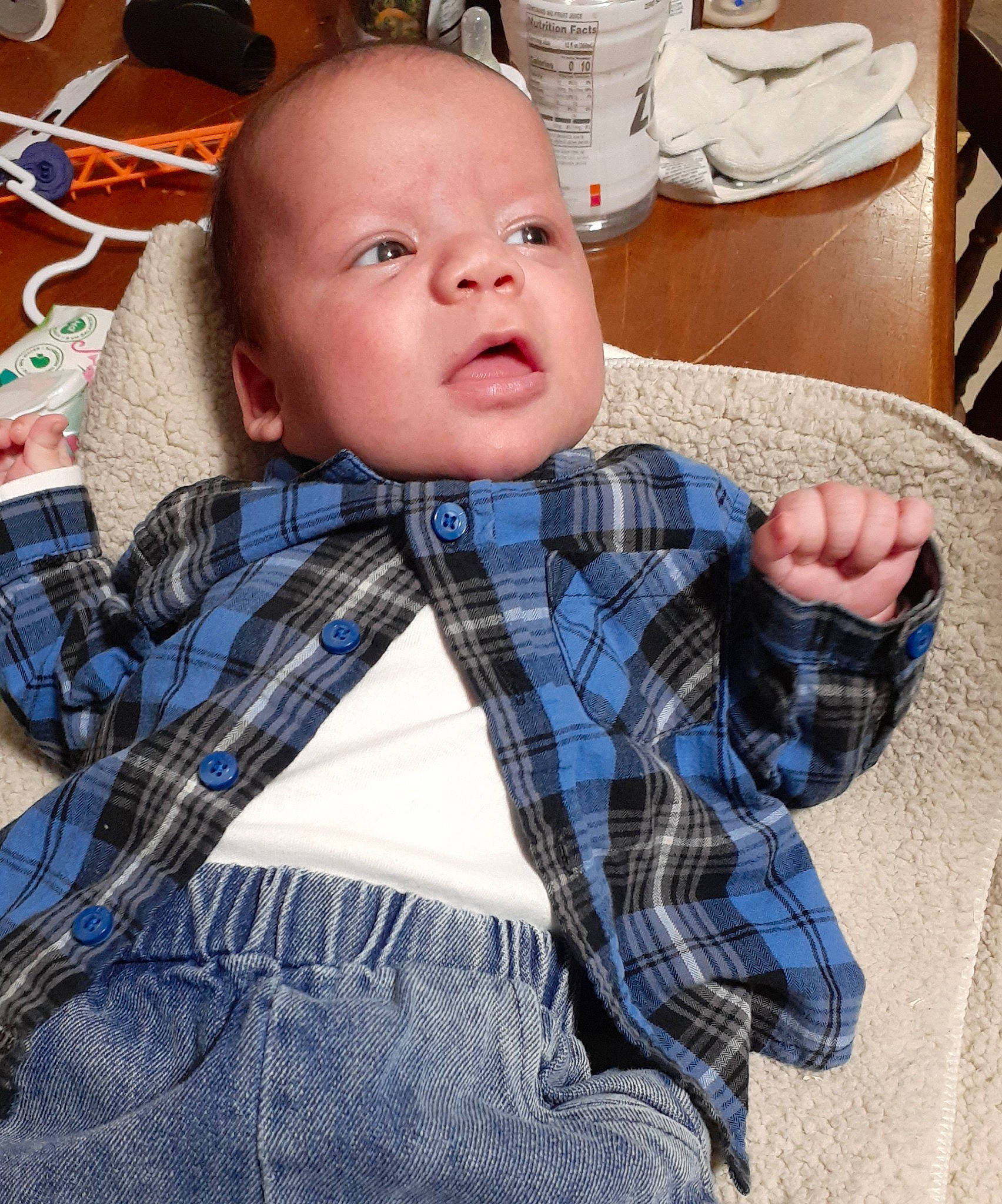 Mateo is registered to the contest to win money with this photo: baby, chair, child, comfort, denim, dress_shirt, eyewear, flooring, happy, pattern, person, plaid, room, sleeve, t_shirt, table, tableware, tartan, textile, toddler