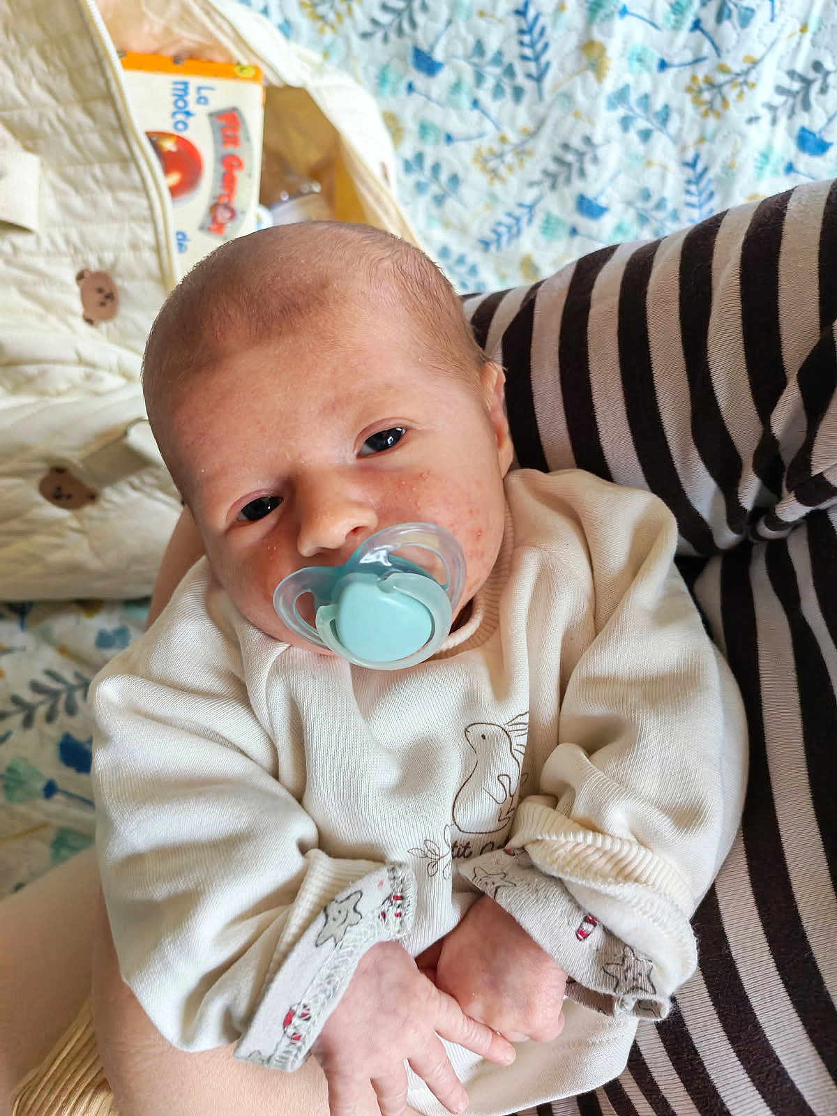 Thiago a rejoint le concours — aidez-le/la à gagner de superbes lots ! baby, infant, newborn, pacifier, onesie, face, eyes, hand, arm, striped_sleeve, blanket, patterned_bed, holding, closeup, indoors, soft_lighting, skin, cute, portrait, baby_book