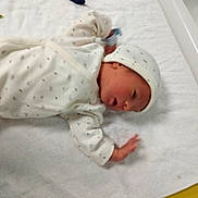 Thiago a rejoint le concours — aidez-le/la à gagner de superbes lots ! baby, newborn, infant, onesie, knit_hat, towel, hospital, medical_wristband, bassinet, crib, portrait, sleeping, face, hand, white_sheet, soft_texture, cute, hospital_room, polka_dots, swaddle