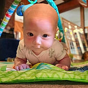 Teagan joined the competition — help win amazing prizes! baby, infant, play_mat, indoor, child, cute, face, eyes, smile, hands, colorful, toy, floor, blanket, person, young_child, crawling, focus, home, soft_lighting